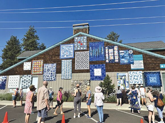 Sisters - Crowd looking at quilts hung on a building