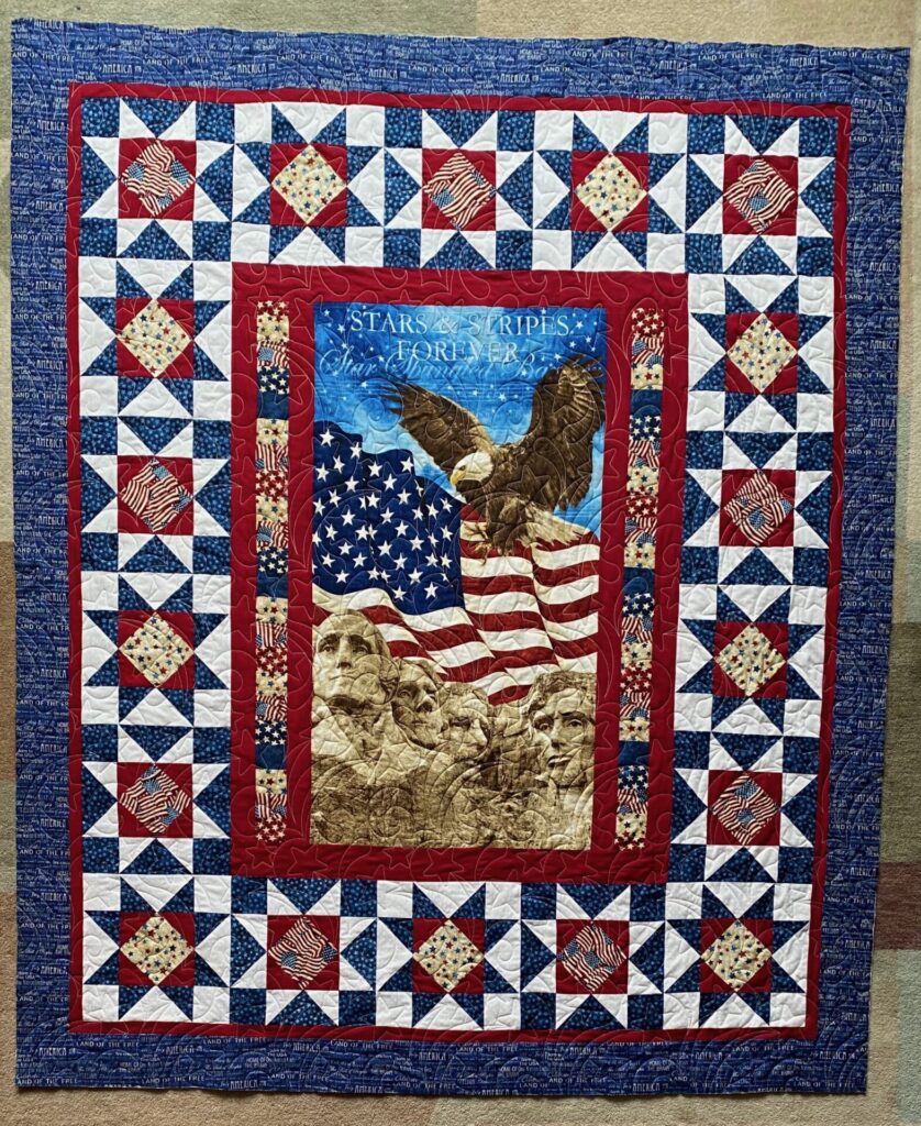 Patriotic quilt with red, white, and blue star blocks and an central eagle motif under the text 'Stars & Stripes Forever'.